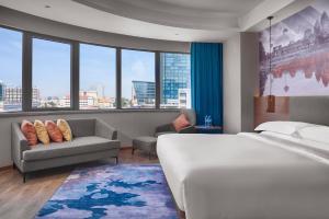 a bedroom with a bed and a couch and windows at Aurea Central Hotel in Phnom Penh