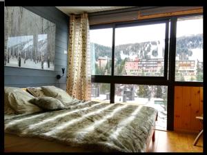 1 dormitorio con cama y ventana grande en Appartement chalet PRA LOUP 1600 La sapinière, en Pra-Loup