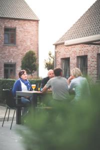 een groep mensen die aan een tafel zitten bij B&B Nieuwhof in Gistel