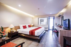 Raming Lodge Hotel في شيانغ ماي: غرفة نوم بسرير ومكتب وتلفزيون