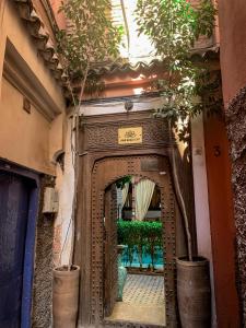 Riad Ghali Hotel & SPA في مراكش: مدخل عماره فيها باب بالنباتات