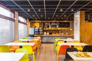 a restaurant with tables and chairs and a counter at ibis budget Paris Porte d'Italie Est in Le Kremlin-Bicêtre