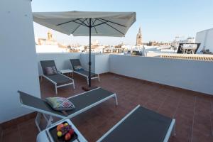 a patio with two chairs and an umbrella on a roof at Céntriko Apartments Francos in Seville