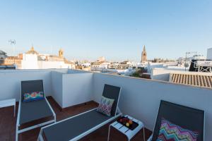a balcony with two chairs and a view of a city at Céntriko Apartments Francos in Seville