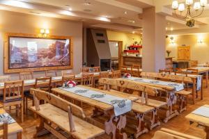 a restaurant with wooden tables and a large painting on the wall at OW Zakopiec in Zakopane