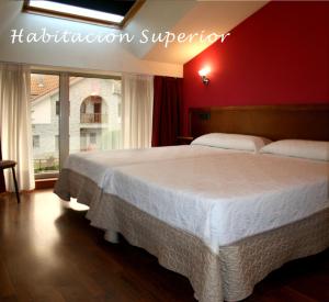 a bedroom with a white bed with a red wall at Hotel Cangas de Onis Center in Cangas de Onís