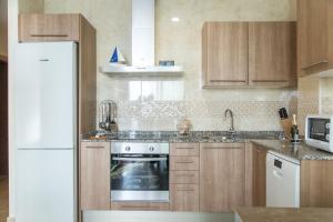 a kitchen with wooden cabinets and a white refrigerator at Melior-1 in Calpe