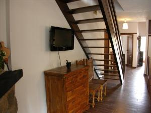 a room with a tv on a wall and a staircase at casa las serijuelas in Villanueva de Ávila