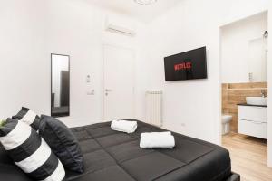 a bedroom with a black bed with a tv on the wall at Black Rooms Colosseo in Rome