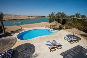 a swimming pool with chairs and umbrellas next to a river at Sunset Villa in El Gouna with Private Heated Pool NEW BEDROOMS ADDED in Hurghada