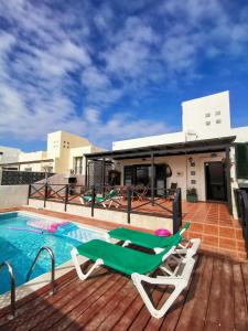 a deck with chairs next to a swimming pool at Paradise Villa in Corralejo