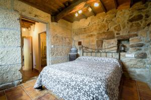 a bedroom with a bed in a stone wall at Gran Casa Rural A Touza in Ourense