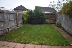 a backyard with a fence and a green yard at Four Chimneys House in Peterborough