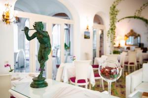 una statua su un tavolo accanto a un bicchiere di vino di Hotel Savoia a Positano