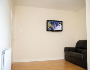 a living room with a couch and a tv on the wall at Carvetii - Derwent House - Spacious 2nd floor flat in Grangemouth