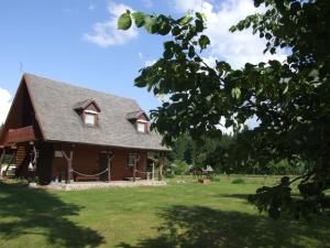 a house with a gambrel roof on a green yard at Apartament Janewiczówka in Kopiec