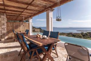 een houten tafel en stoelen op een patio met uitzicht bij Bella Vista Ereikousa in Ereikoússa