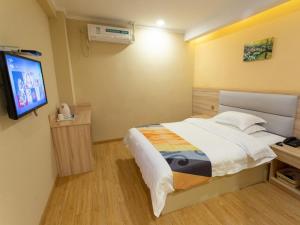 Un dormitorio con una cama y un televisor de pantalla plana. en Shell Zhenjiang Xijindu Jinshan Park Hotel, en Zhenjiang
