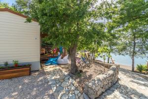 a house with a tree and a stone wall at Krk Mobile Homes in Klimno