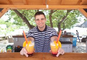 a man sitting at a table with two drinks at Krk Mobile Homes in Klimno