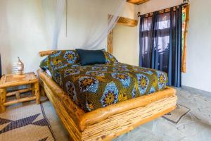 a bedroom with a bed with a comforter and a table at Kivu Paradis Resort in Nyamyumba