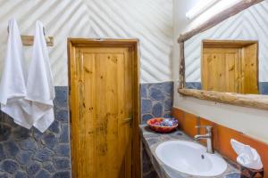 a bathroom with a sink and a wooden door at Kivu Paradis Resort in Nyamyumba