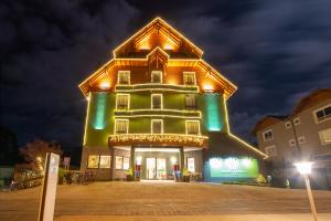 a large green building with lights on it at night at Hotel Laghetto Viale in Gramado