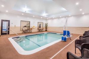 a swimming pool in a room with chairs and tables at Holiday Inn Express & Suites - Albany Airport - Wolf Road, an IHG Hotel in Albany