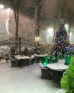 un árbol de Navidad y mesas y sillas en la nieve en Shine House Hotel, en Adler