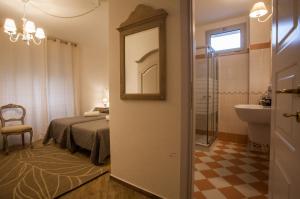a hotel room with a bed, chair and a mirror at City Garden Guest House in Olbia