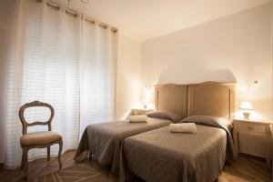 a hotel room with a bed, chair, and nightstand at City Garden Guest House in Olbia