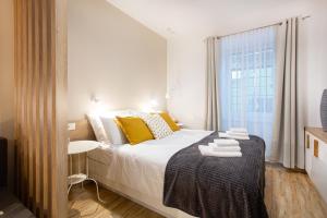 Un dormitorio con una cama con almohadas amarillas y una ventana en Apartments Tivoli, en Liubliana