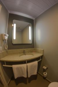 a bathroom with a sink with a mirror and towels at ibis Catalao in Catalão