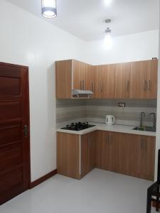 a kitchen with wooden cabinets and a stove top oven at Equator Holiday Inn in Fuvahmulah