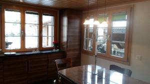 cocina con armarios de madera, mesa y ventanas en Chalet Bärgblick en Grindelwald