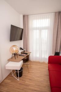 a living room with a desk and a red couch at Design Hotel Sophie´s in Norderney