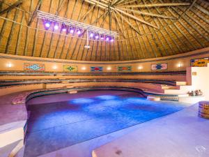 - une piscine dans un bâtiment avec toit dans l'établissement aha Lesedi African Lodge & Cultural Village, à Pelindaba