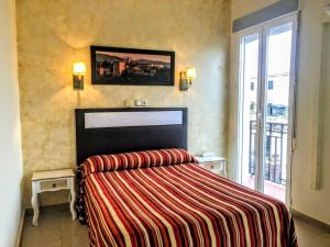 a bedroom with a bed with a striped blanket at Hostal Sonia Granada in Granada