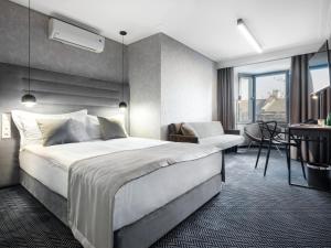 a hotel room with a large bed and a desk at Hotel Logos Kraków in Krakow