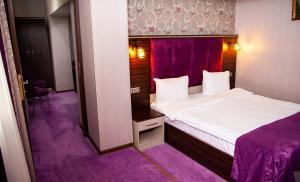 Mildom Hotel Baku في باكو: غرفة نوم بسرير وسجاد ارجواني