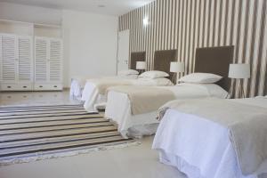 a white room with four beds and a rug at Villa Franca in Rio de Janeiro