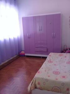 1 dormitorio con 1 cama y armario púrpura en Casarão com piscina e churrasqueira, en Río de Janeiro