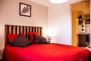 a red bed with red pillows in a bedroom at le Pic vert in Surzur