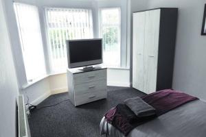 a bedroom with a tv on a dresser with a bed at Outstanding and Spacious modern 4 bedroom house in Hull