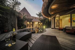 una terraza de madera con sillas y una chimenea en una casa en Luxury Villas Merci Resort 3BR Seminyak #2 en Kuta