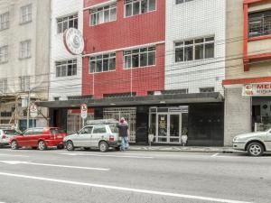 a man standing in front of a red and white building at Hotel Cervantes in Curitiba