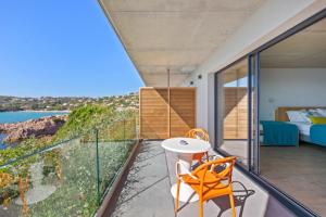 a room with a balcony with a view of the ocean at Hotel le Jardin d'Emile in Porticcio