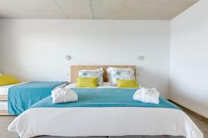 a bedroom with two beds with blue and yellow pillows at Hotel le Jardin d'Emile in Porticcio