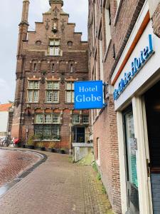 un vecchio edificio in mattoni con un cartello blu della guida dell'hotel di Hostel The Globe ad Amsterdam