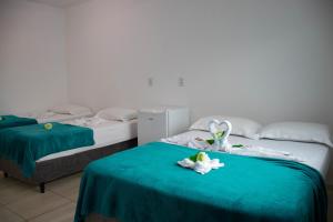 two beds with green sheets and white flowers on them at Pousada Graff in Penha +76 photos